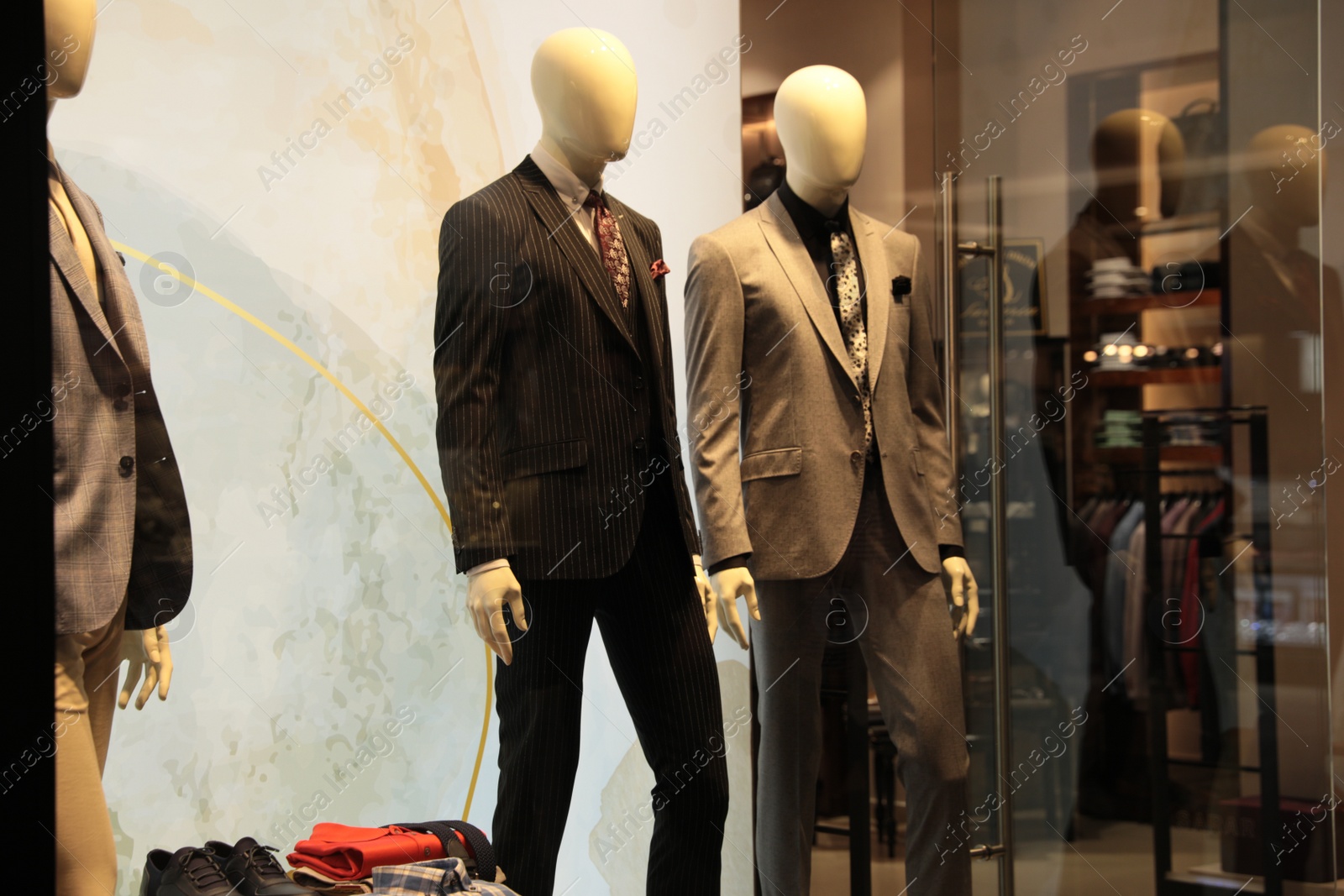 Photo of Beautiful suits on mannequins in showcases of fashion store