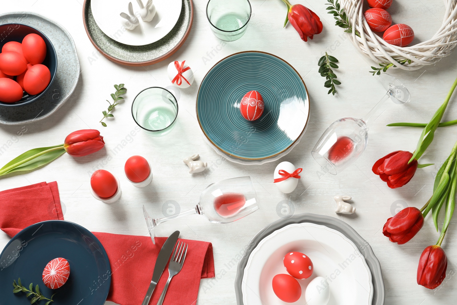 Photo of Festive Easter table setting with painted eggs on wooden background, flat lay