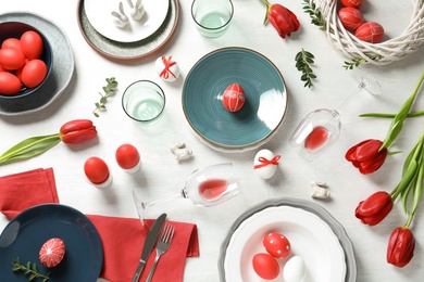 Photo of Festive Easter table setting with painted eggs on wooden background, flat lay