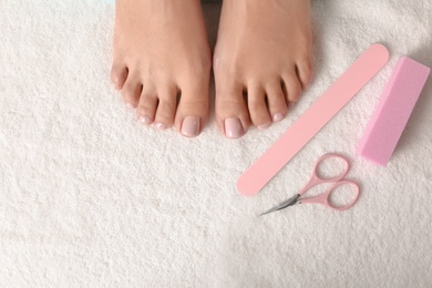 Photo of Top view of woman with beautiful feet and pedicure accessories on white towel, space for text. Spa treatment