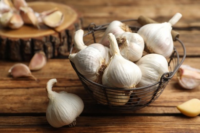 Photo of Fresh organic garlic in basket on wooden table