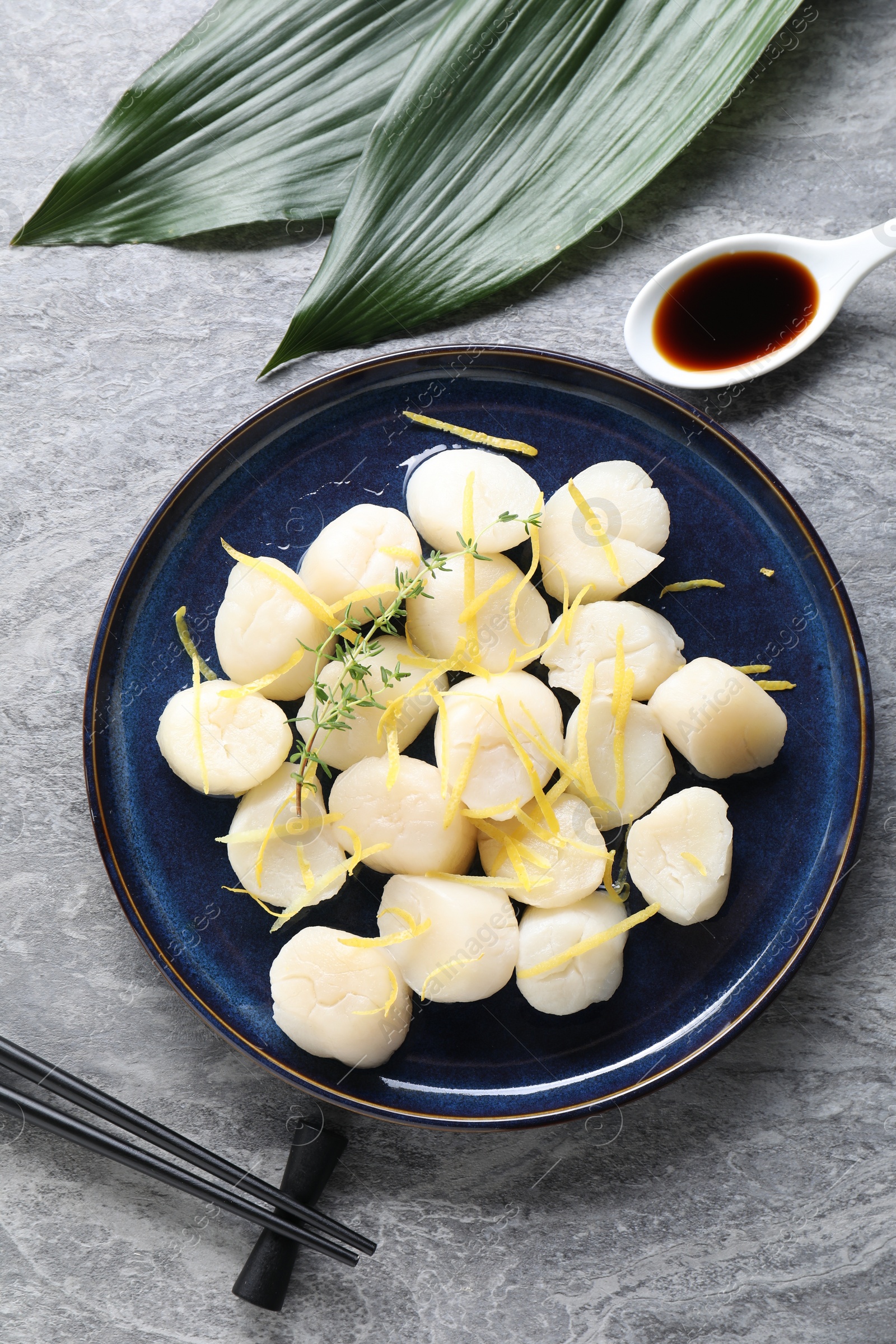 Photo of Raw scallops with thyme and lemon zest served on grey marble table, flat lay