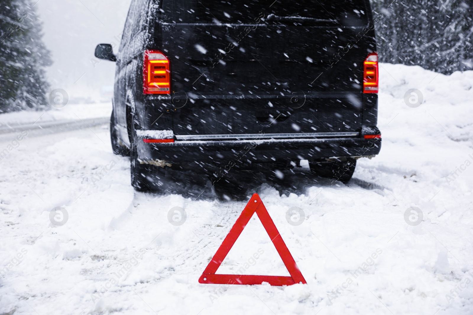 Photo of Emergency stop sign and modern car on snowy road