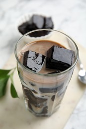 Photo of Glass of milk with grass jelly on table, closeup