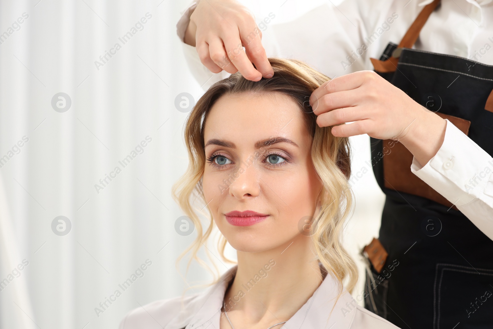 Photo of Hair styling. Professional hairdresser working with client in salon, closeup. Space for text