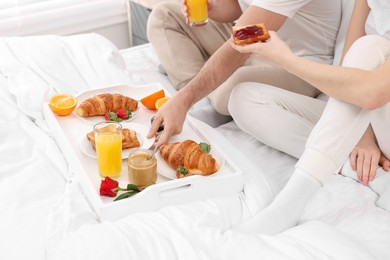 Photo of Couple eating tasty breakfast on bed, closeup