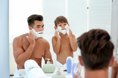 Photo of Father and son having fun while applying shaving foam in bathroom