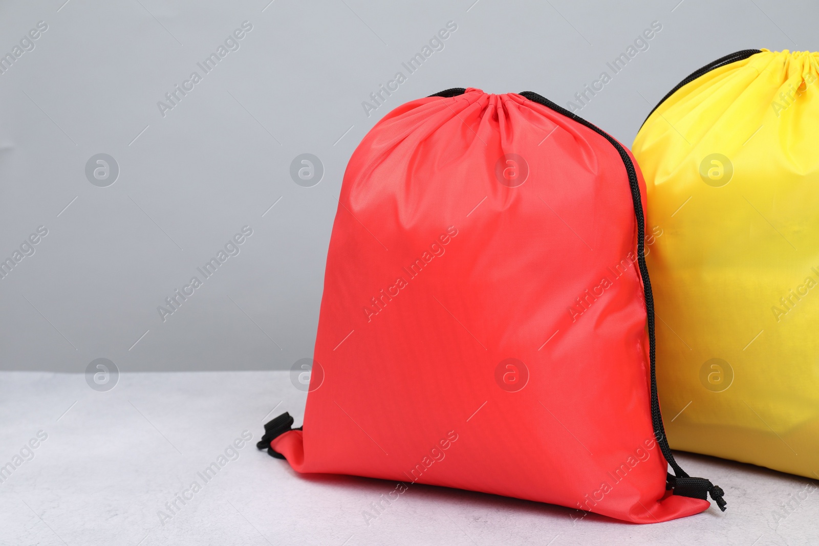 Photo of Two drawstring bags on light textured table. Space for text