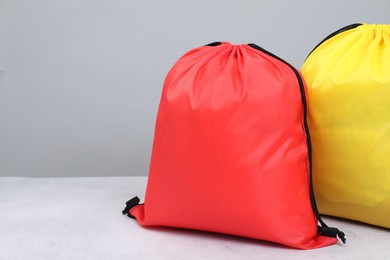 Photo of Two drawstring bags on light textured table. Space for text