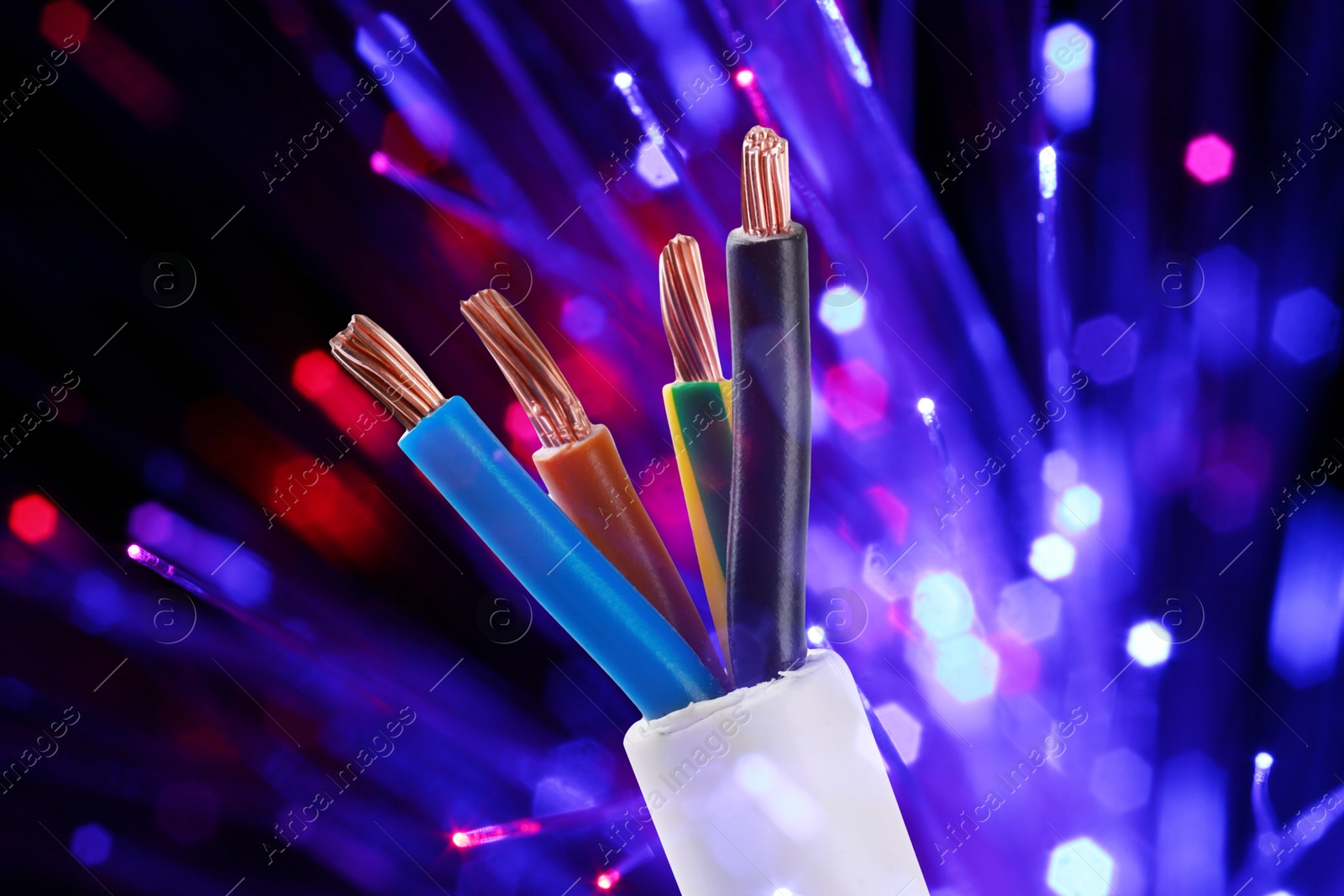 Image of Colorful electrical wires against dark background with blurred lights, closeup. Bokeh effect