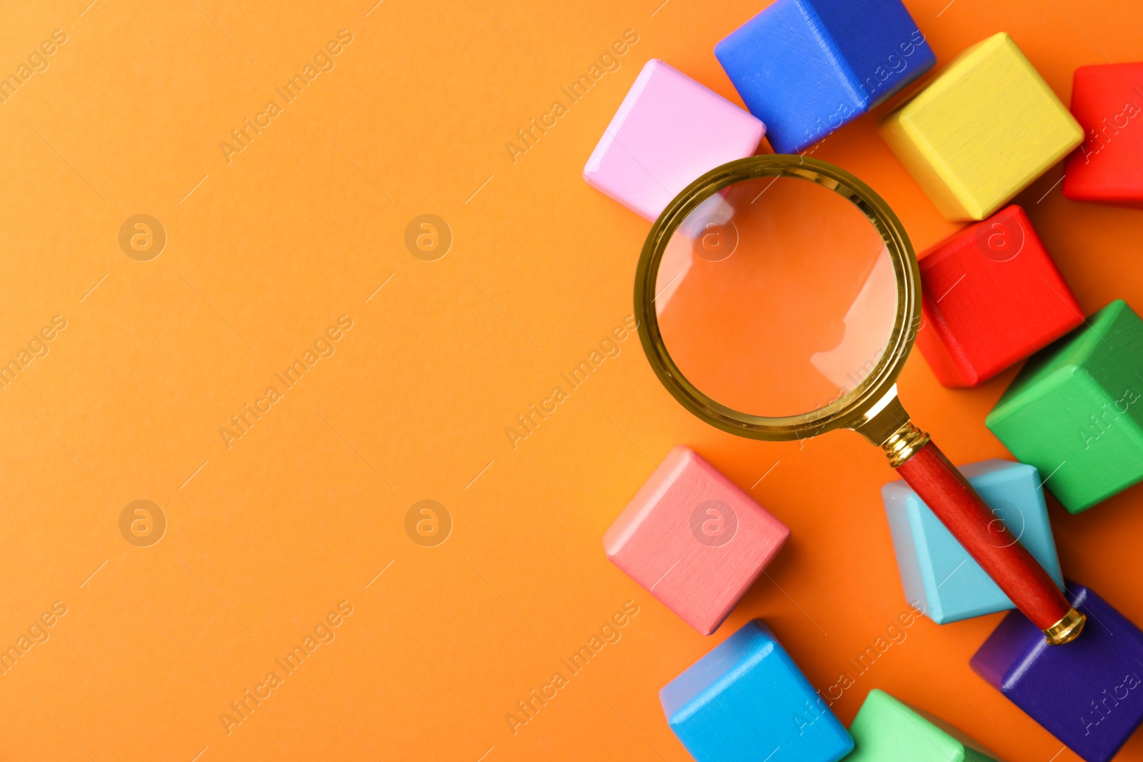 Photo of Different colorful cubes and magnifier glass on orange background, flat lay with space for text. Find keywords concept