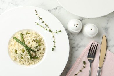Photo of Delicious risotto with asparagus served on marble table, flat lay