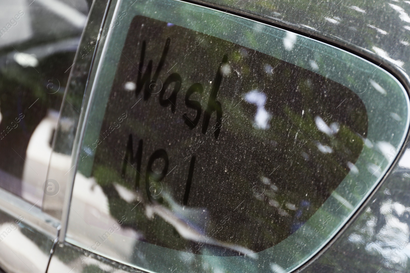 Photo of Written text WASH ME on dirty car window, closeup