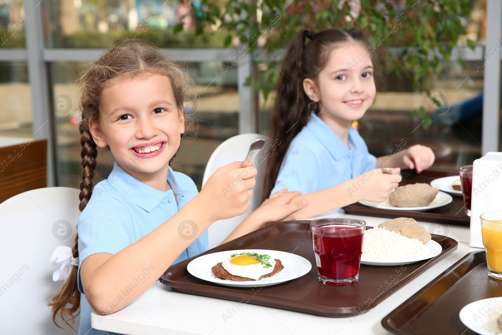 Photo of Cute children at table with healthy food in school canteen