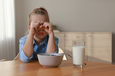 Cute little girl crying and refusing to eat breakfast at home