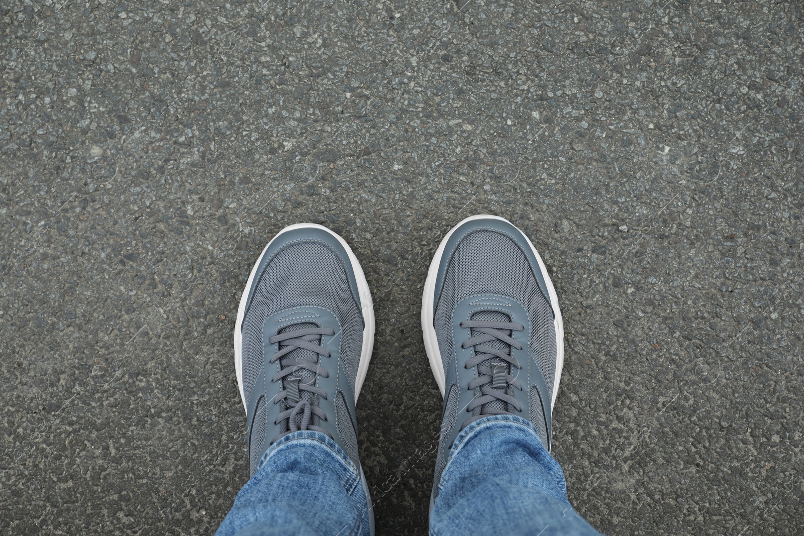 Photo of Man in sneakers standing on asphalt, top view