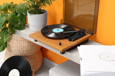 Photo of Stylish turntable with vinyl record on console table indoors