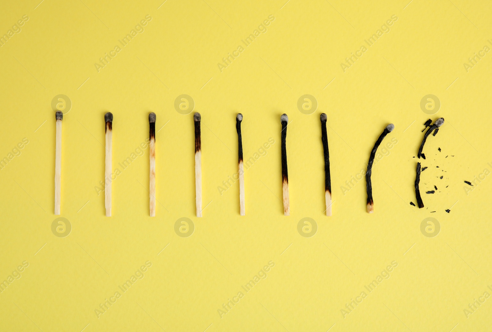 Photo of Different stages of burnt matches on yellow  background, flat lay