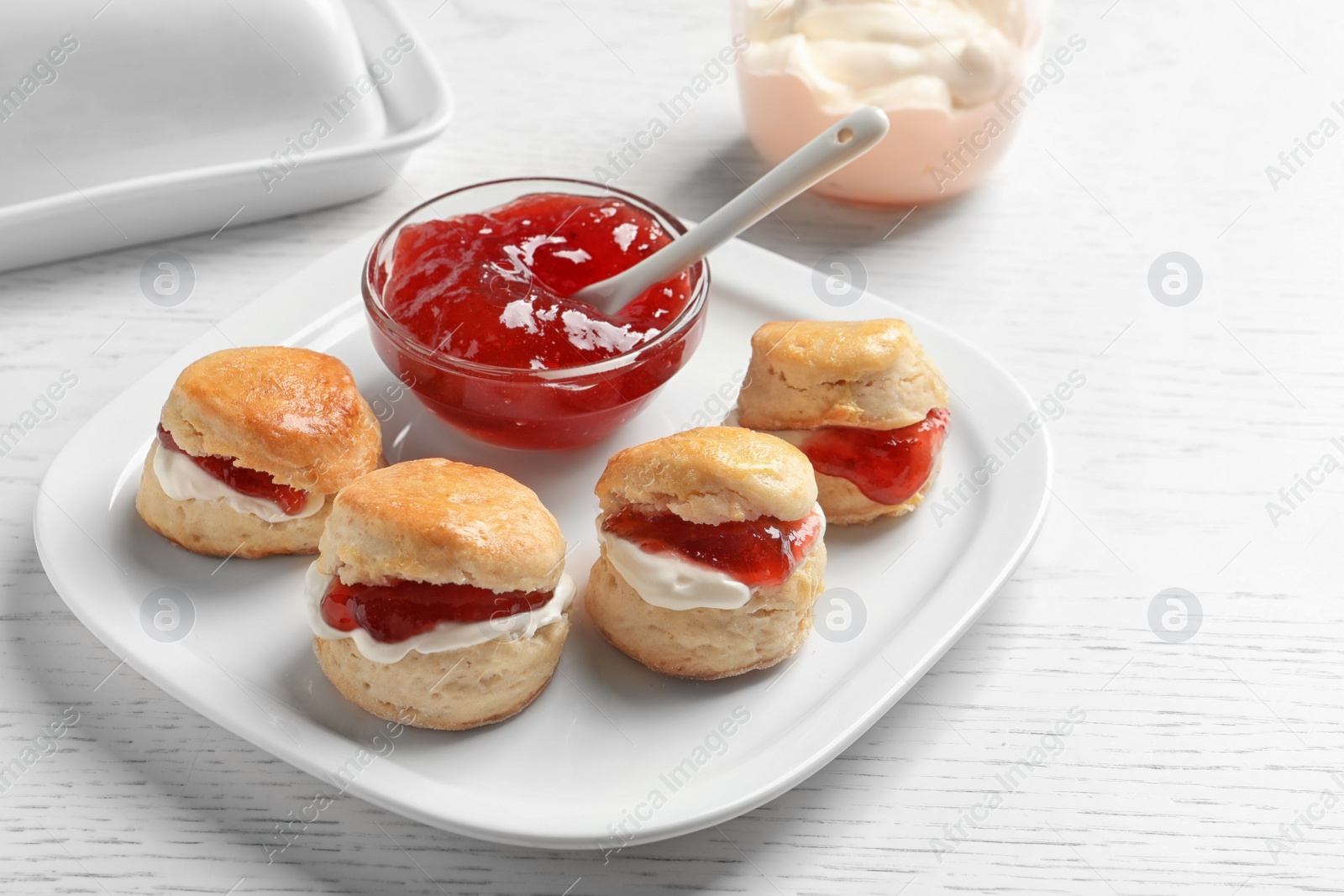 Photo of Tasty scones with clotted cream and jam on light background