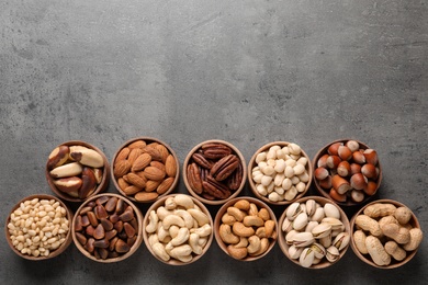 Photo of Flat lay composition with organic nuts and space for text on grey background, top view. Snack mix