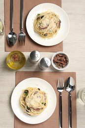 Photo of Delicious pasta with anchovies, olives and parmesan cheese served on light wooden table, flat lay