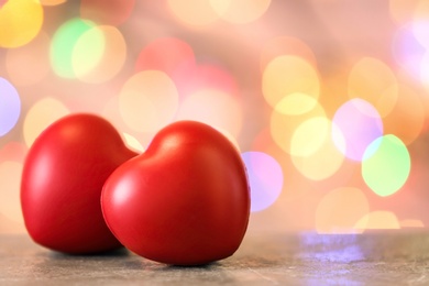 Red hearts on table against blurred lights. Space for text