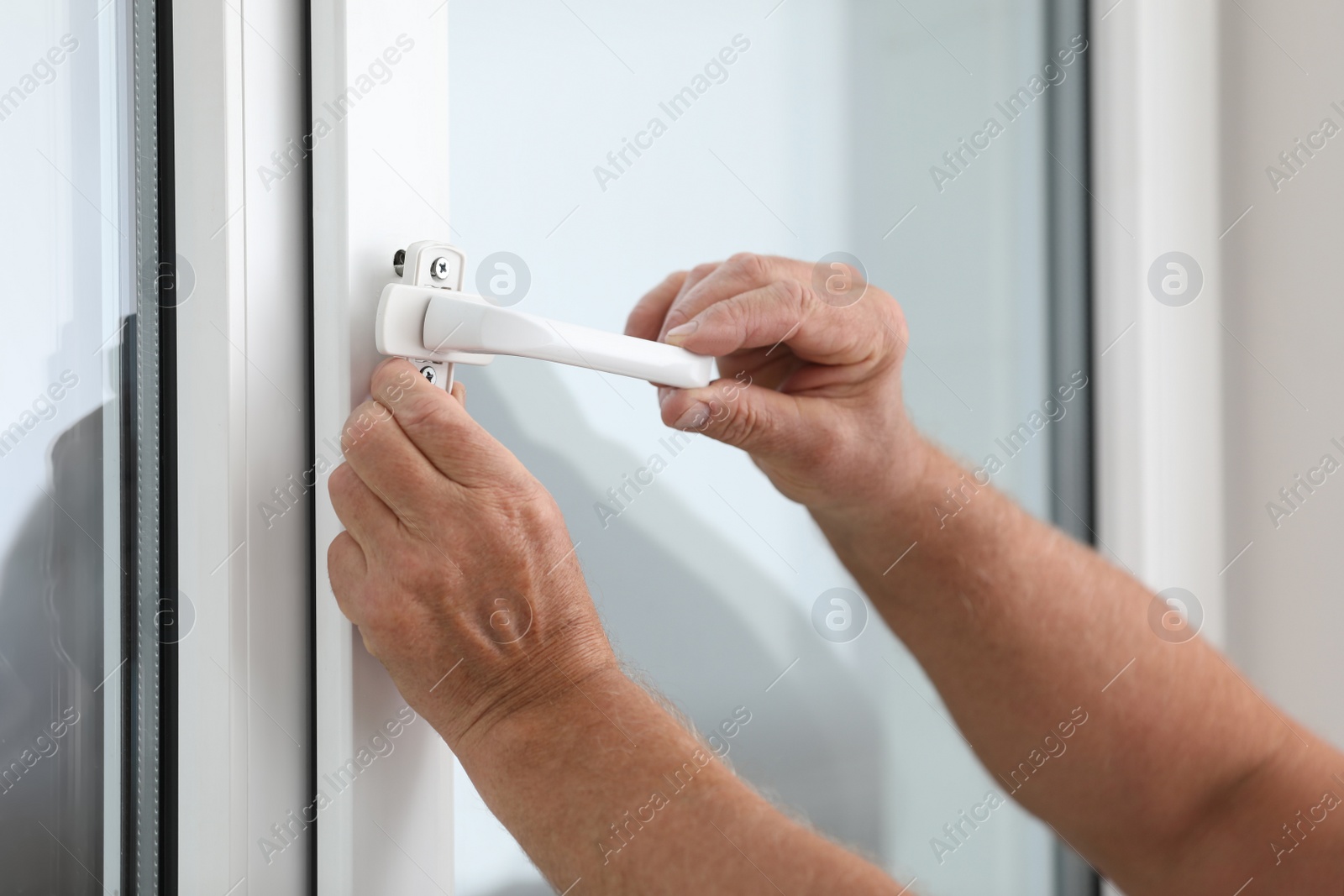 Photo of Mature construction worker repairing plastic window indoors