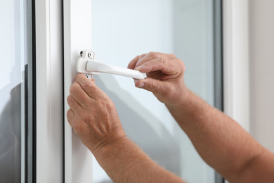 Mature construction worker repairing plastic window indoors