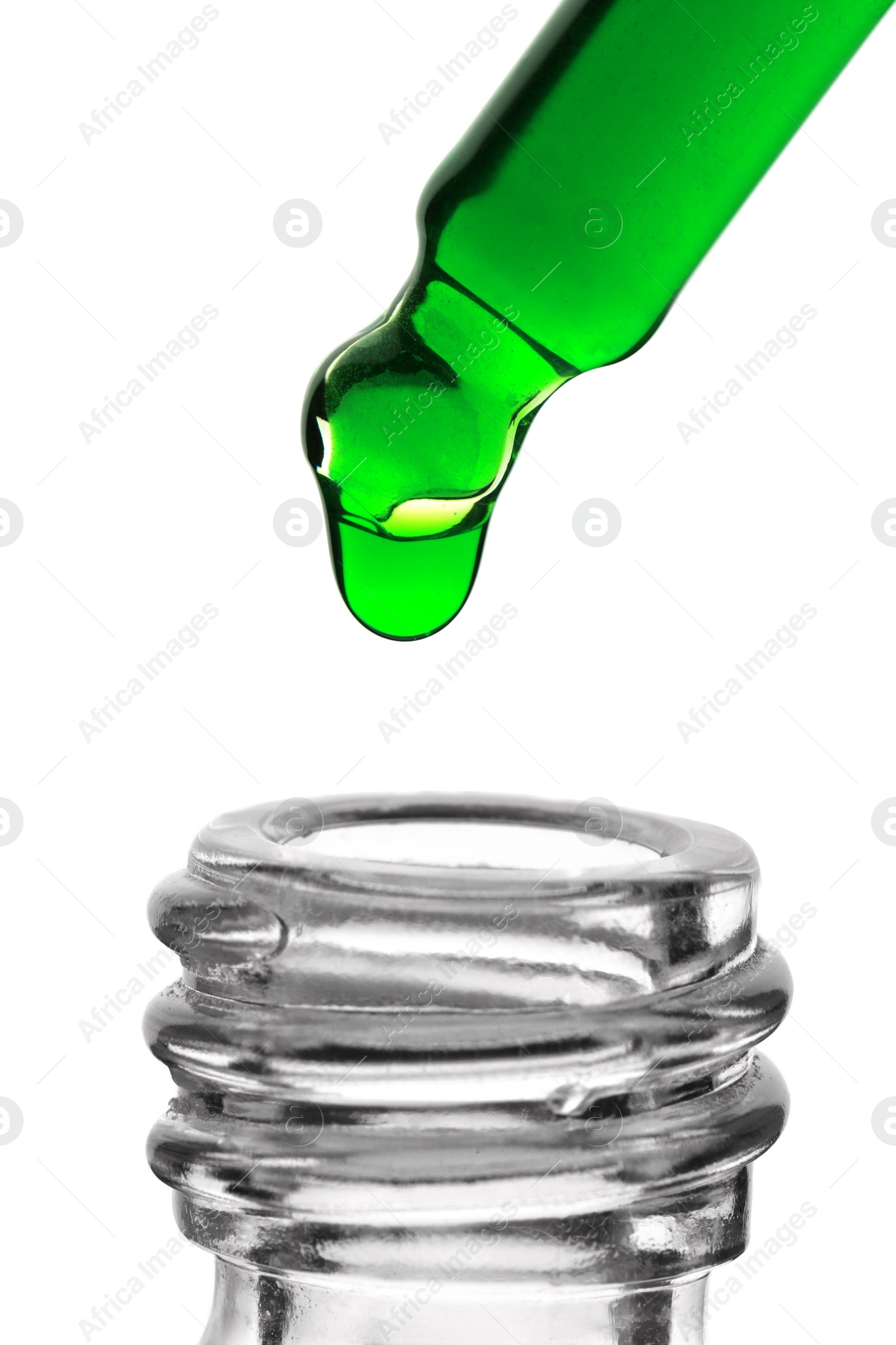 Photo of Dripping green facial serum from pipette into glass bottle on white background, closeup