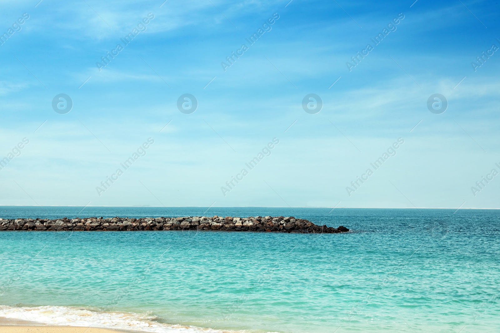Photo of Picturesque view of ocean with rock breakwater on sunny day