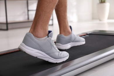Photo of Man training on walking treadmill at home, closeup