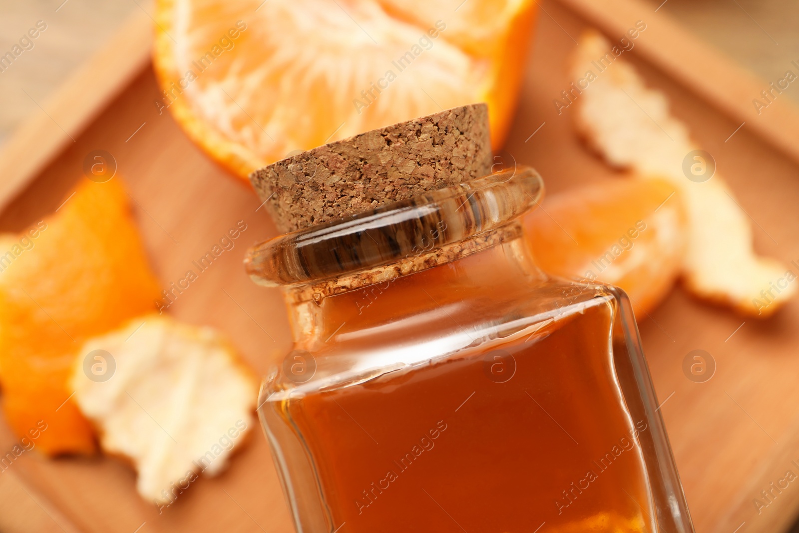 Photo of Bottle of tangerine essential oil and fresh fruit on table, top view