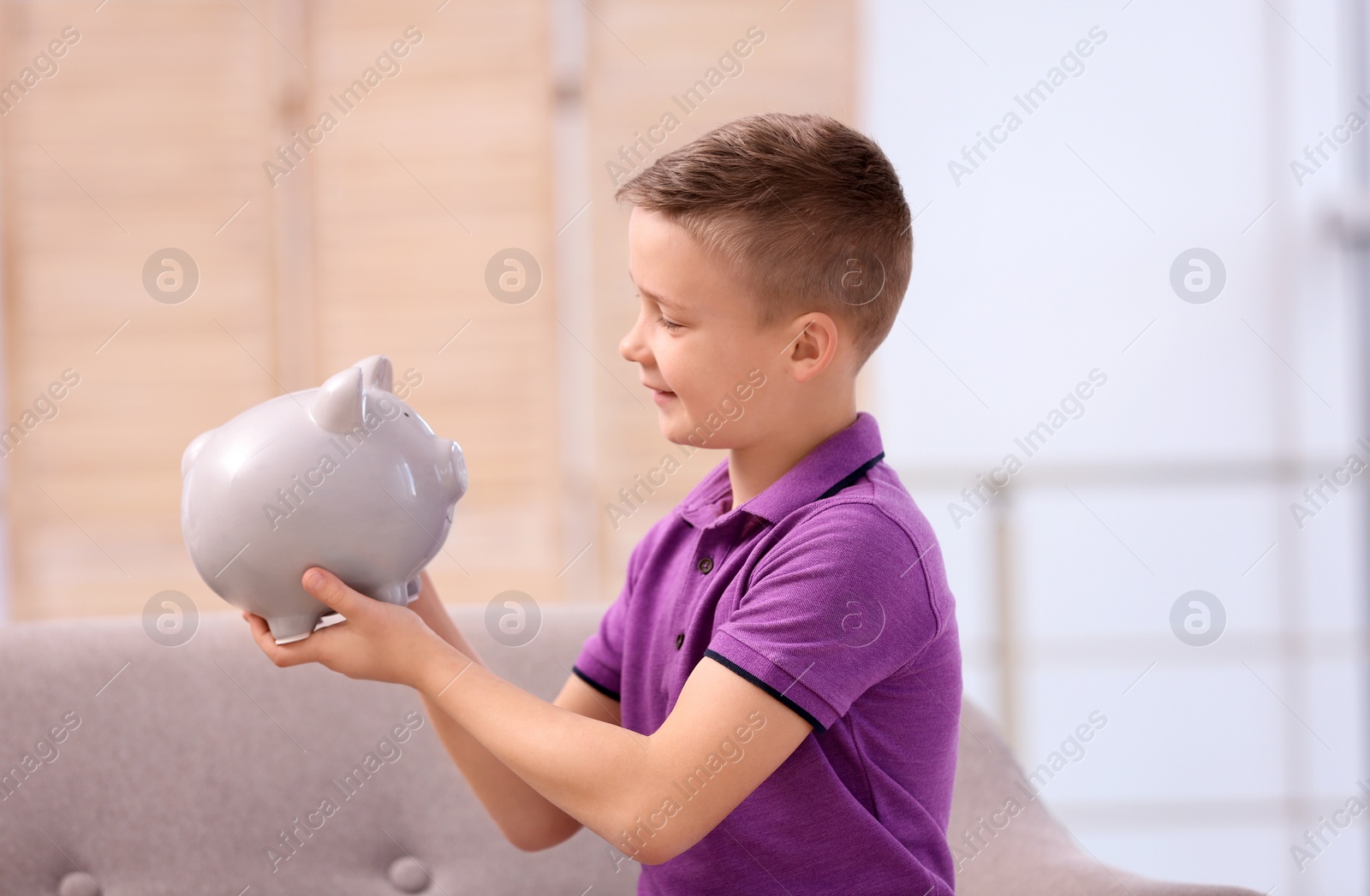 Photo of Little boy with piggy bank at home