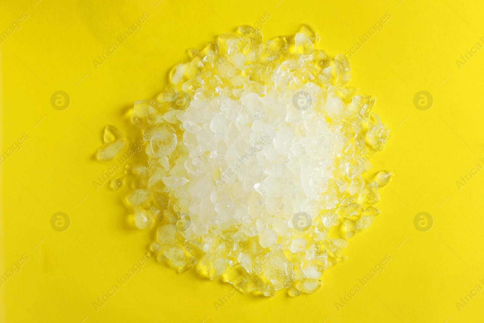 Photo of Pile of crushed ice on yellow background, top view