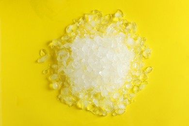 Photo of Pile of crushed ice on yellow background, top view