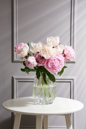 Beautiful peonies in glass vase on white table