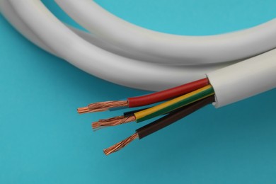 Photo of Electrical wires on light blue background, closeup