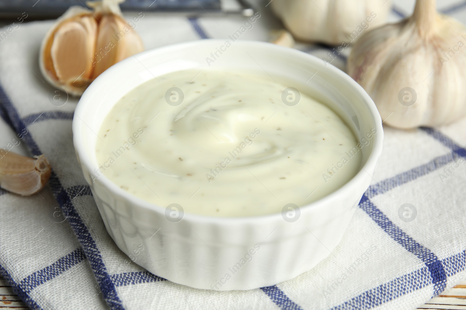 Photo of Composition with bowl of garlic sauce on plaid fabric