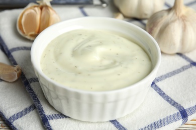 Photo of Composition with bowl of garlic sauce on plaid fabric