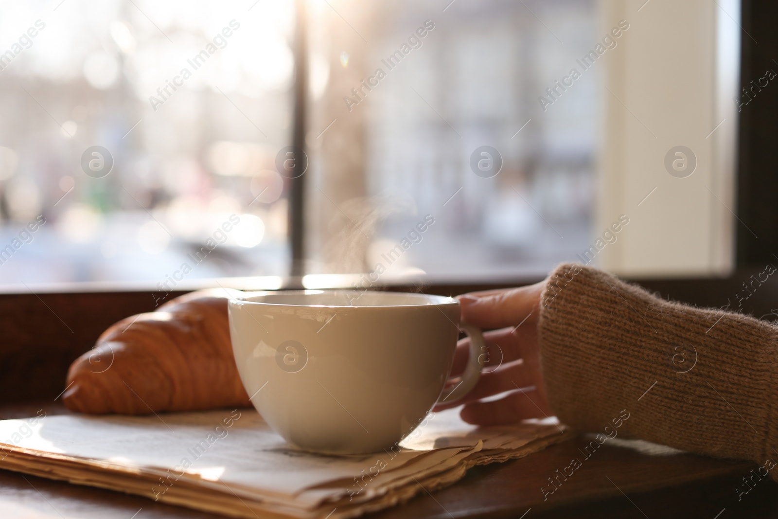 Photo of Woman with cup of delicious morning coffee near window indoors