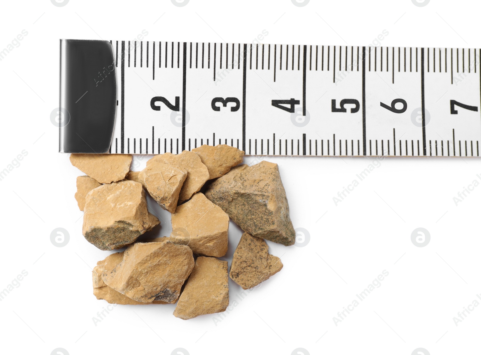 Photo of Pile of kidney stones and measuring tape on white background, top view