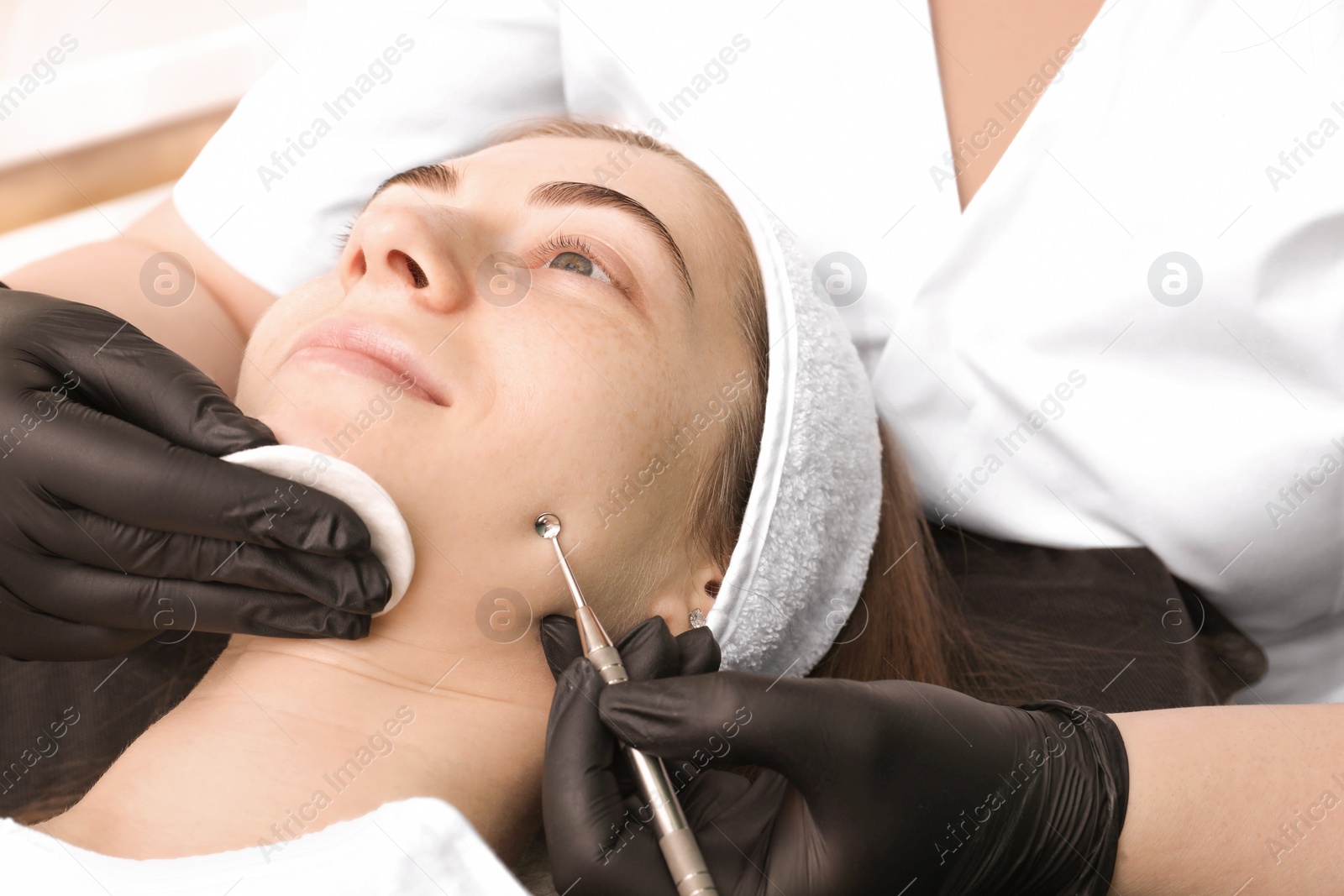 Photo of Cosmetologist using scrubber, closeup. Client having cleansing procedure