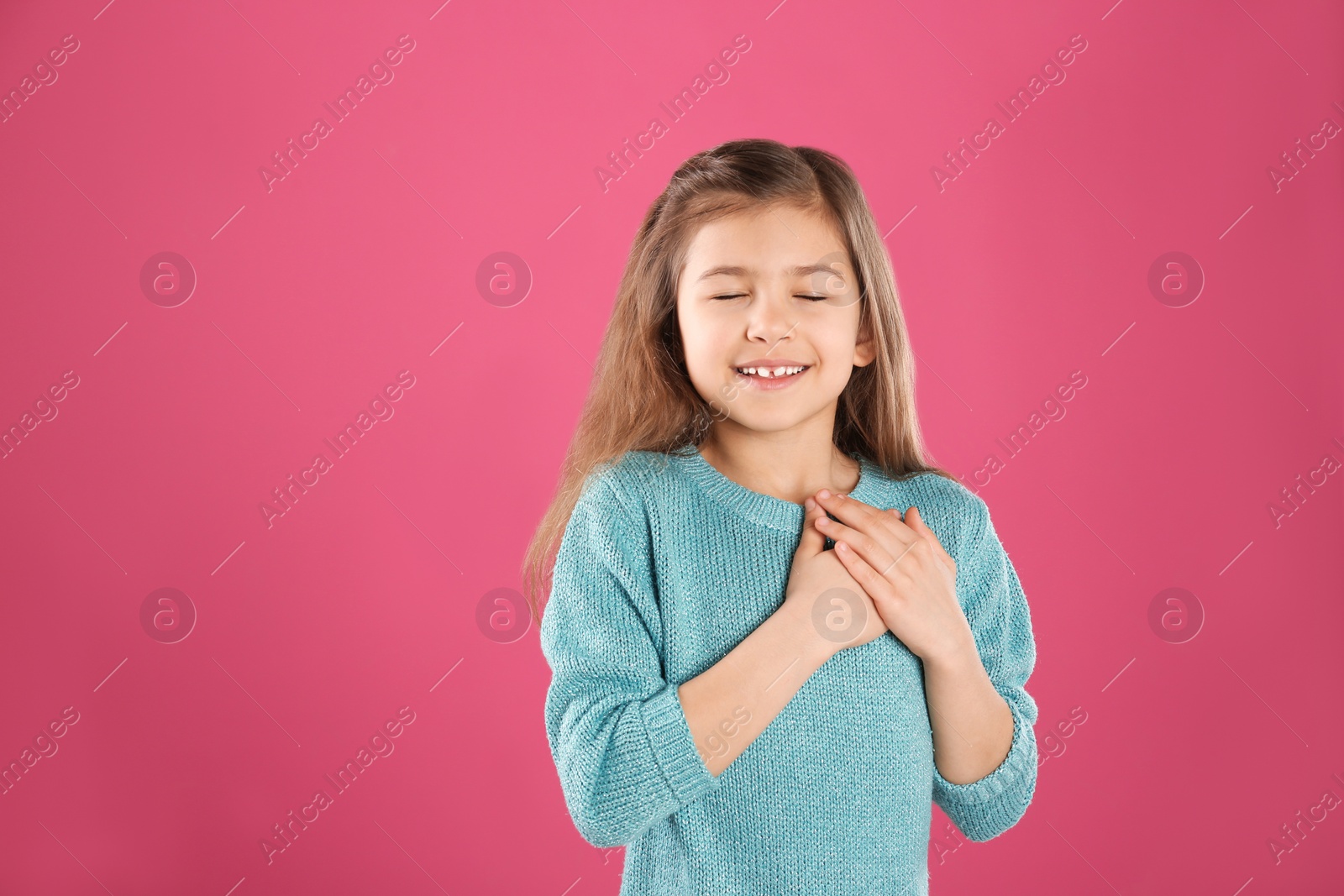 Photo of Portrait of girl holding hands near her heart on color background. Space for text