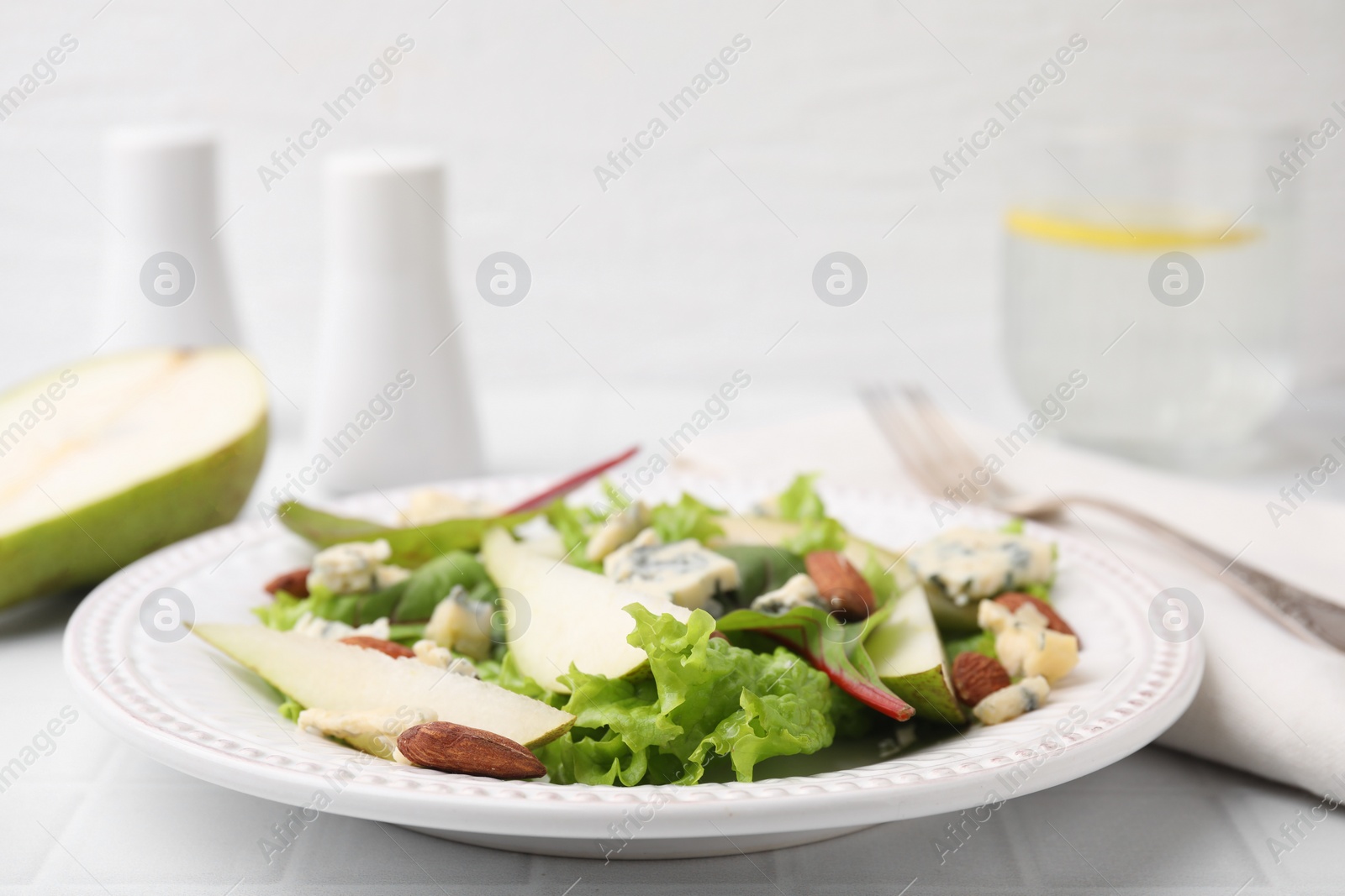 Photo of Delicious pear salad on white tiled table, closeup