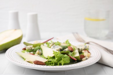 Photo of Delicious pear salad on white tiled table, closeup