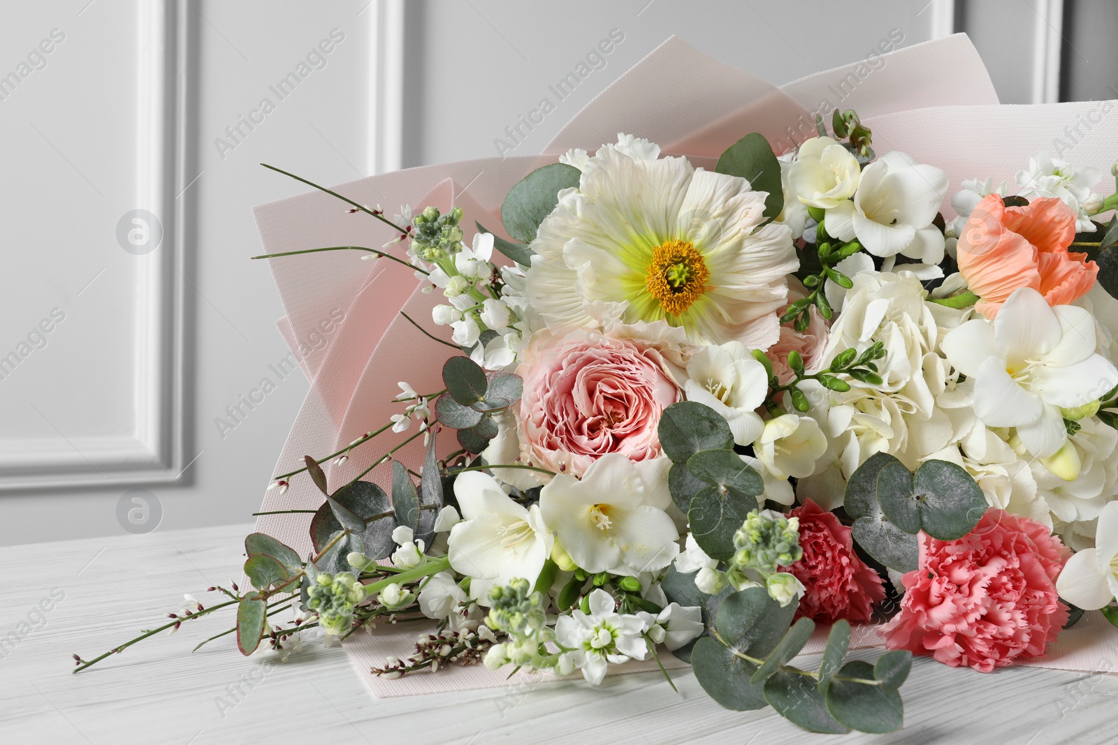 Photo of Bouquet of beautiful flowers on white wooden table, closeup