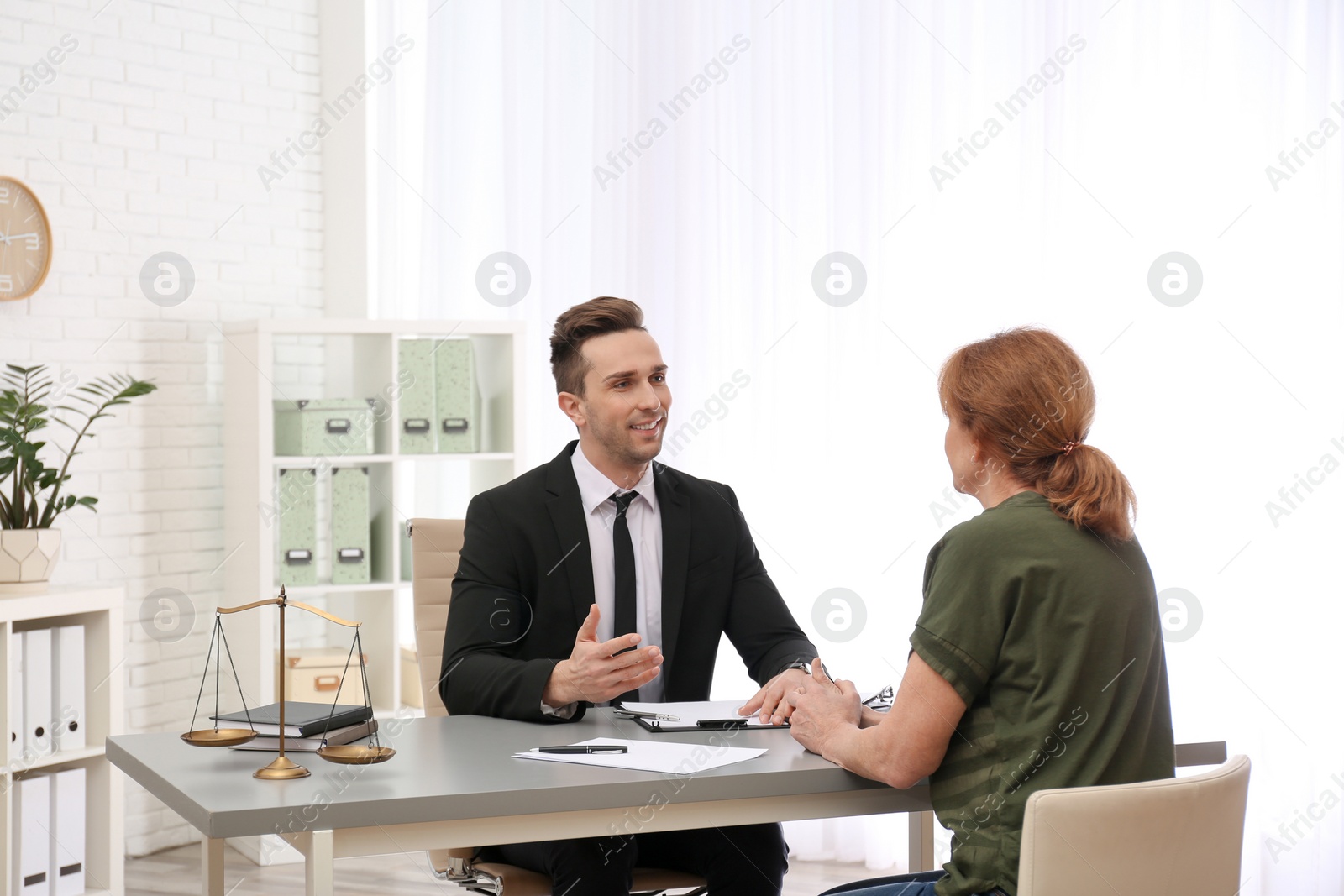 Photo of Young lawyer having meeting with senior client in office