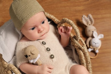 Cute little baby with knitted bear toy in wicker basket