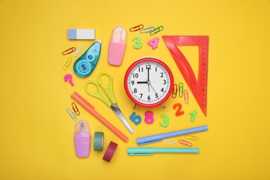 Flat lay composition with different school stationery and alarm clock on yellow background. Back to school