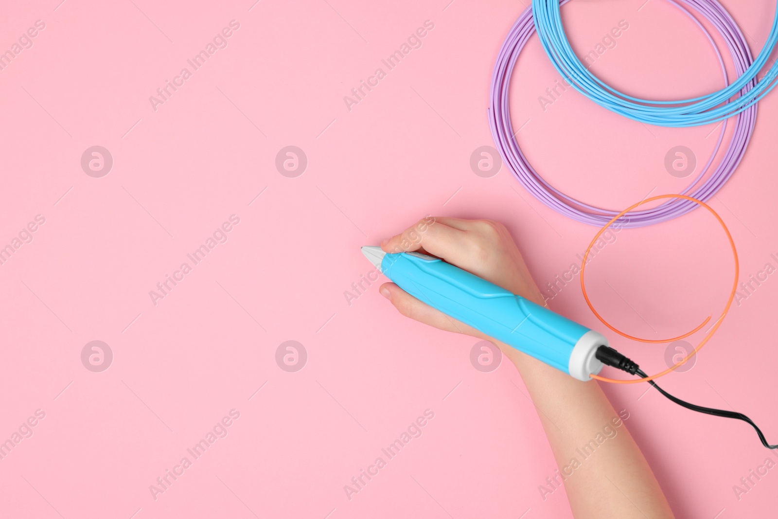 Photo of Boy drawing with stylish 3D pen on pink background, top view. Space for text